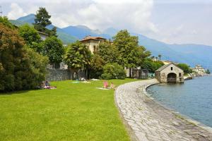 a group of people sitting on the grass by the water at Appartamento Lotte in Cannobio