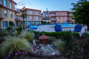 a courtyard with a garden with a pool and buildings at Mappy Holidays Aparthotel in Sozopol