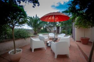 a group of white chairs and an umbrella on a patio at B&B Brunone in Alberobello