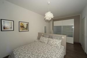 ベッラーノにあるCasa Luisaの白いベッドルーム(ベッド1台、シャンデリア付)