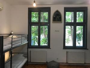 a room with three windows and a staircase and a bed at Passpartout Hostel in Timişoara
