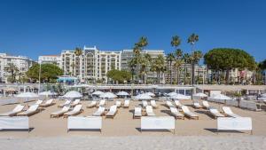 a group of lounge chairs and umbrellas on a beach at 7 Croisette in Cannes
