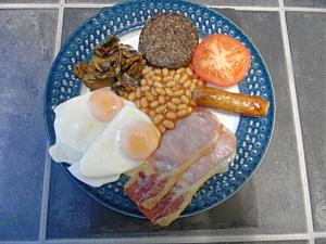 a blue plate of food with eggs bacon beans and tomatoes at Craik Na Dav B&B in Invermoriston