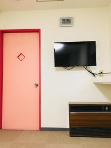 Zimmer mit einer roten Tür und einem Flachbild-TV in der Unterkunft Guesthouse Masago in Urakawa