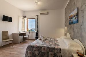 a bedroom with a bed and a desk and a window at Il vecchio e il mare in San Vito lo Capo