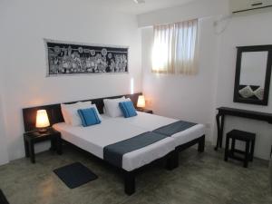 a bedroom with a large bed with blue pillows at Ripple Reach Apartments in Galle