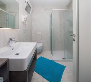 a bathroom with a white sink and a blue rug at Apartmani Kos in Supetar +47 photos