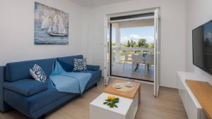 a living room with a blue couch and a tv at Apartmani Kos in Supetar