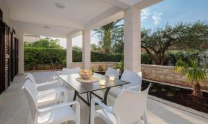 a patio with a table and white chairs at Apartmani Kos in Supetar