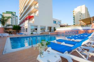 una piscina con tumbonas junto a un edificio en Gandia Playa, en Gandía