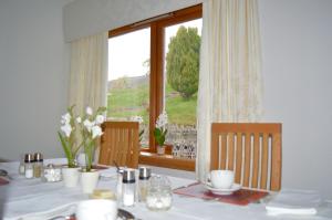 a table with a white table cloth and a window at Strathview Lodge in Dornoch