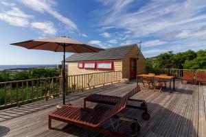 una terraza de madera con mesa y sombrilla en Azul Singular, en Horta