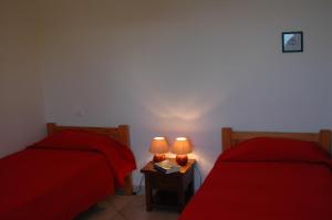 2 Betten in einem Zimmer mit roter Bettwäsche und Lampen in der Unterkunft Residence Capicciolo in Olmeto