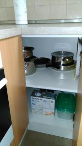 a kitchen shelf with pots and pans and a box at Apartman Mima in Banja Luka
