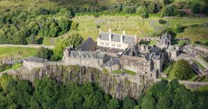 um velho castelo no topo de uma colina com árvores em Castlehill Apartment em Stirling