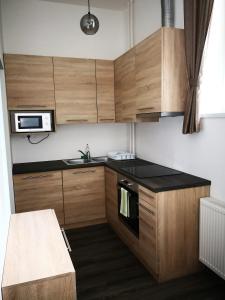 a small kitchen with wooden cabinets and a microwave at MATE Apartmanok in Tiszaújváros