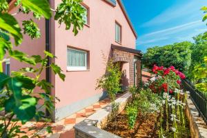 a pink house with flowers in front of it at Apartment Salha in Nova Vas