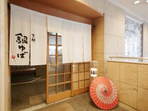 una puerta a un edificio con una sombrilla roja en APA Hotel Takaoka-Marunouchi, en Takaoka
