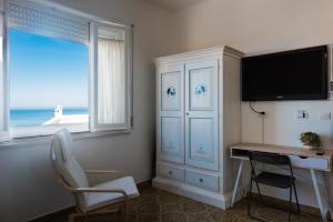 a room with a desk and a television and a desk and chair at B&B BentueMari in Portoscuso