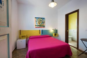een slaapkamer met een bed met een roze deken bij B&B BentueMari in Portoscuso