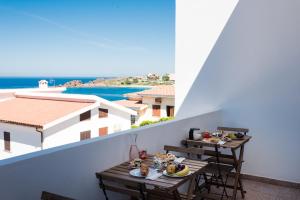 een balkon met een tafel met eten en uitzicht op het water bij B&B BentueMari in Portoscuso