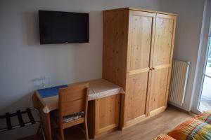 a room with a desk and a cabinet and a tv at Pension Weinberg in Mörbisch am See