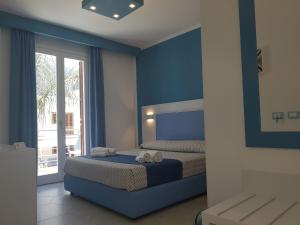 - une chambre bleue avec un lit et des serviettes dans l'établissement B&B Aloe Comfort Rooms, à San Vito Lo Capo