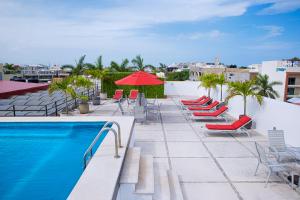 a swimming pool with lounge chairs and a red umbrella at Hotel Los Itzaes by 5th av in Playa del Carmen