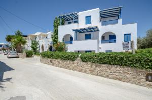 un edificio blanco con una pared de piedra junto a una calle en Hotel Francesca, en Agios Prokopios