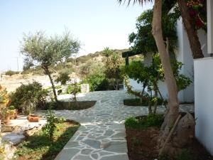 een tuin met bomen en een stenen loopbrug bij Manolis Farm Guest House in Aliko Beach