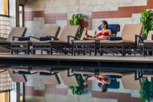 a woman sitting in a chair next to a swimming pool at Grand Hotel Gozo in Għajnsielem