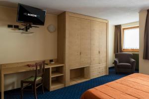 Pokój hotelowy z biurkiem i telewizorem na ścianie w obiekcie Hotel Nordik w mieście Santa Caterina Valfurva