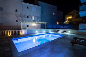 una piscina illuminata di notte di Apartments Sara a Bol