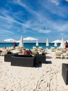 una playa con sillas y sombrillas y el océano en Appartement Le Palais Des Iles en Cannes