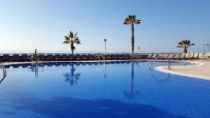 a large swimming pool with chairs and palm trees at Apartamentos Turísticos Augustus in Cambrils