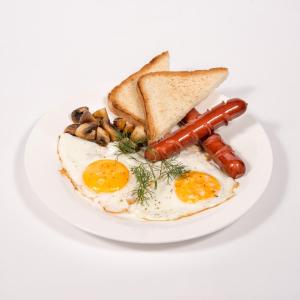 a plate of eggs and toast with sausage and mushrooms at Hotel Kazakhfilm in Almaty