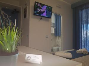 a room with a tv on the wall and a bathroom at B&B Aloe Comfort Rooms in San Vito lo Capo