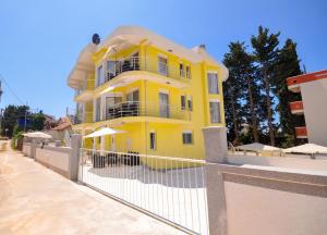 uma casa amarela com uma cerca em frente em Villa Medusa Apartments em Dobra Voda