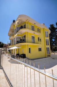 a yellow house with a fence in front of it at Villa Medusa Apartments in Dobra Voda