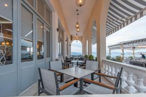 a balcony with tables and chairs and a view of the ocean at Klimis Hotel in Spetses