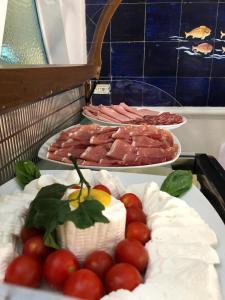 a table topped with cakes and tomatoes and meats at Albergo Gatto Bianco in Capri