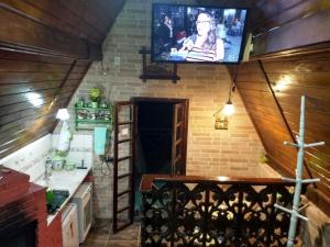 a kitchen with a tv on a brick wall at Chales Alpes Germanicos in Monte Verde