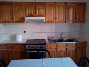 uma cozinha com armários de madeira, um fogão e um lavatório em B1 Apt Mytilini em Mitilene
