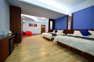 a hotel room with two beds and a blue wall at De Mei Homestay in Qimei