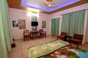 a bedroom with a bed and chairs and a tv at National Guest House in Jalandhar