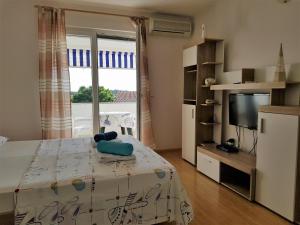 Schlafzimmer mit einem Bett, einem TV und einem Fenster in der Unterkunft Apartments MONICA Novalja in Novalja