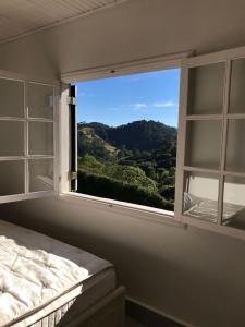 1 dormitorio con ventana y vistas a la montaña en Chalé Serra do Luar, en Santo Antônio do Pinhal