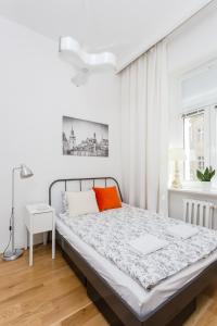 Dormitorio blanco con cama con almohada naranja en Sawa Apartment, en Varsovia