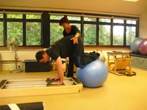 a woman watching a man on a stability ball in a gym at BnBinB La Cour Enchantée in Brugairolles