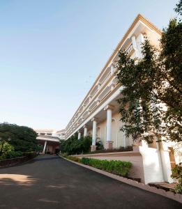 a large white building with columns and a driveway at The Lagoona Resort in Lonavala